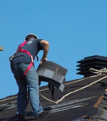 construction man roofer working on roof removing shingles repair